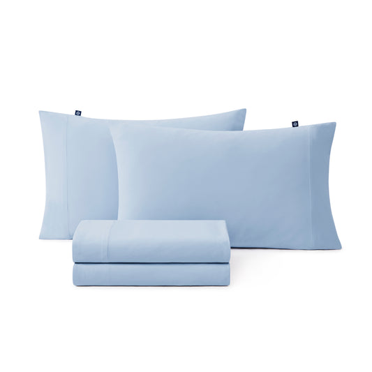 Cooling sheet set in airy coastal bedroom setting – light blue sheets and pillowcases.