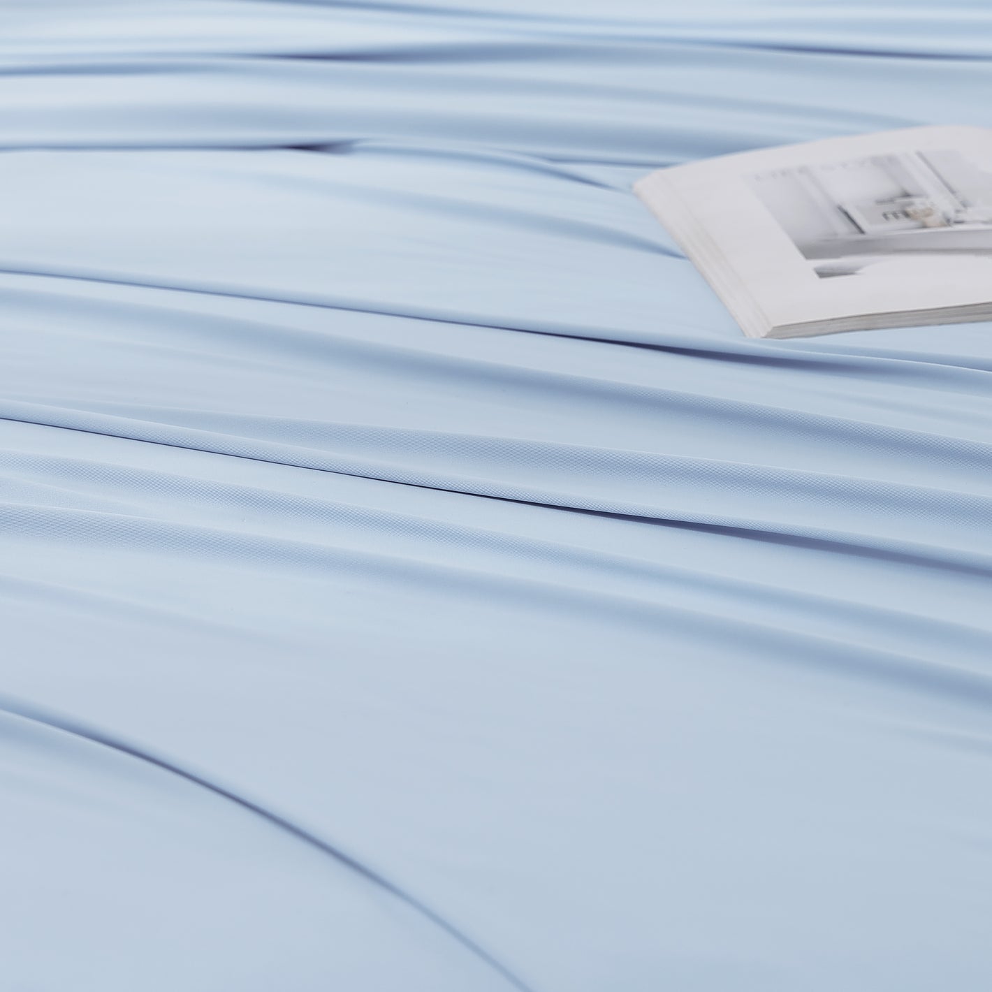Close-up of cooling sheet fabric showing smooth breathable weave in light blue.
