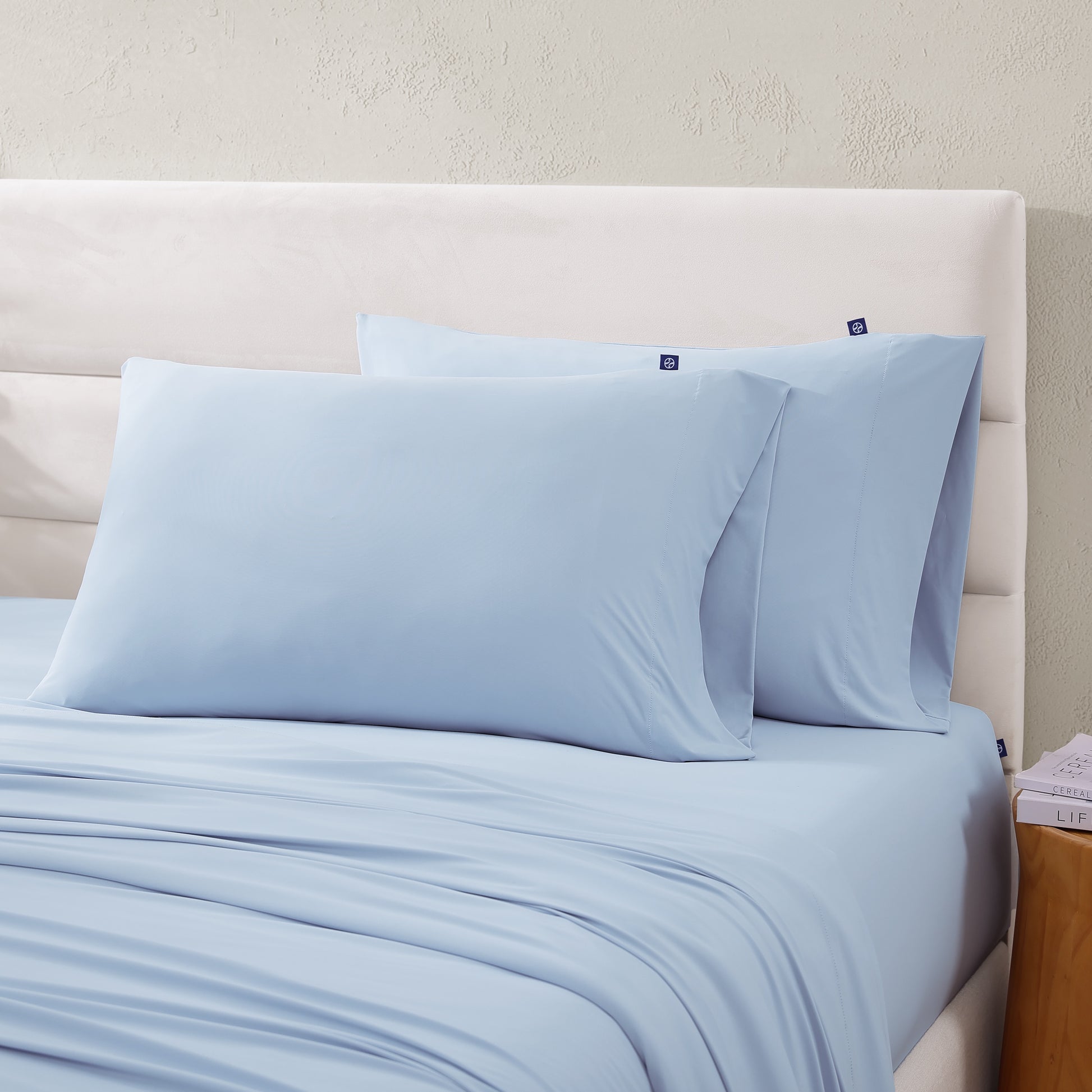 Pair of light blue cooling pillowcases on bed as part of the sheet set.