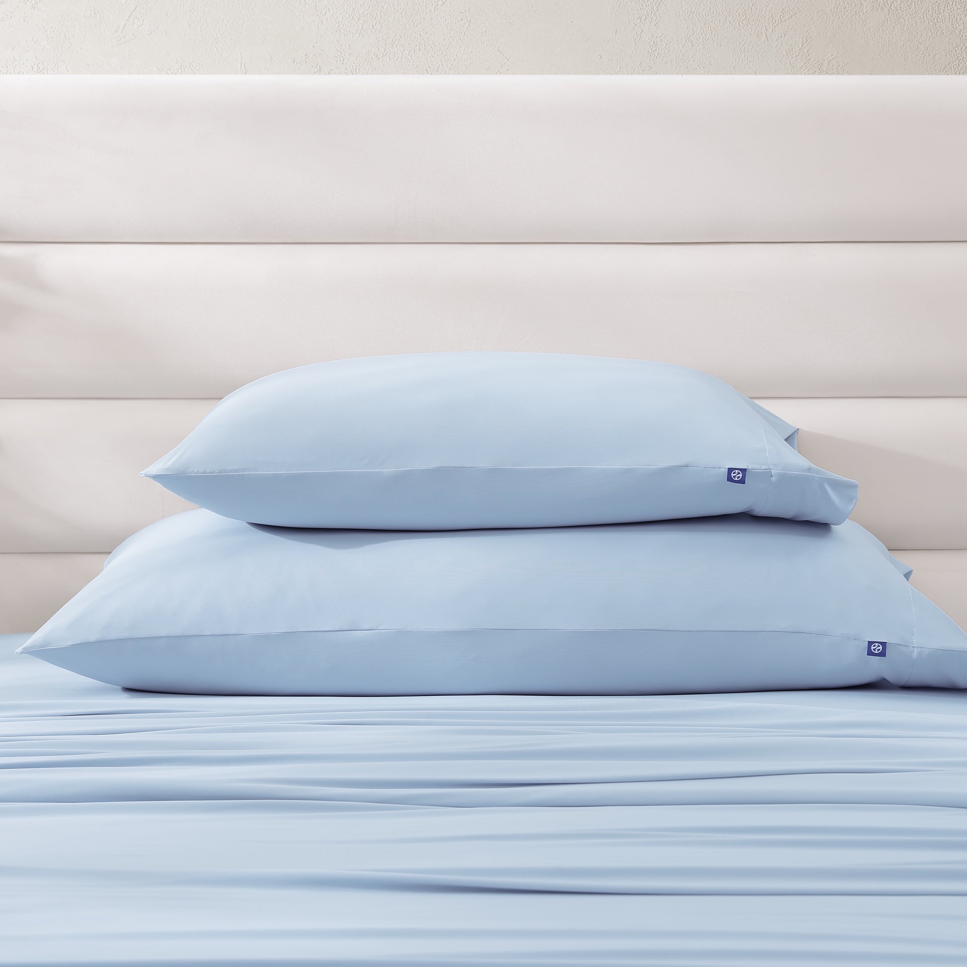 Stack of standard and king cooling pillowcases in light blue, part of sheet set collection.