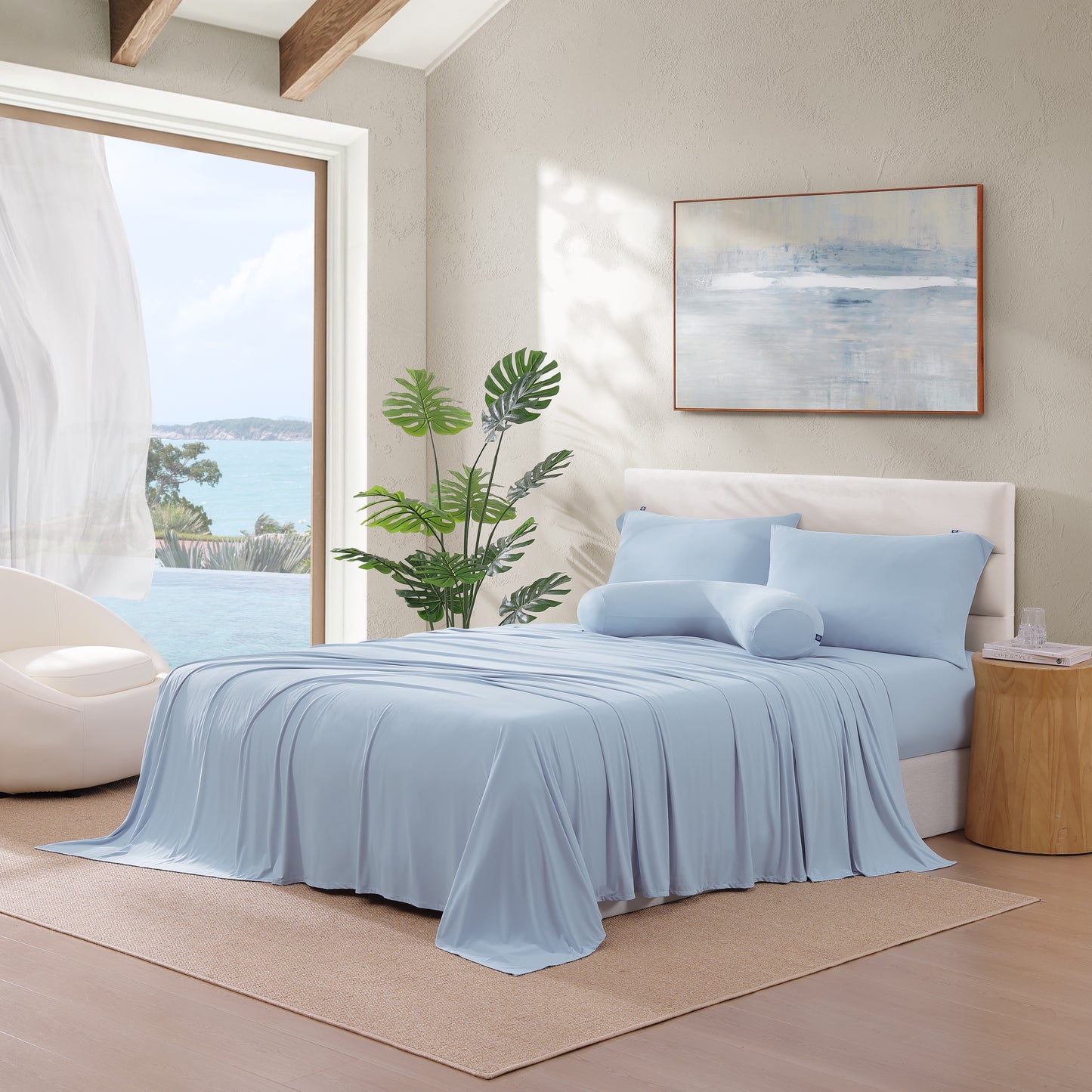 Bedroom scene with bed dressed in blue cooling pillowcases and sheets, styled with natural light and décor.